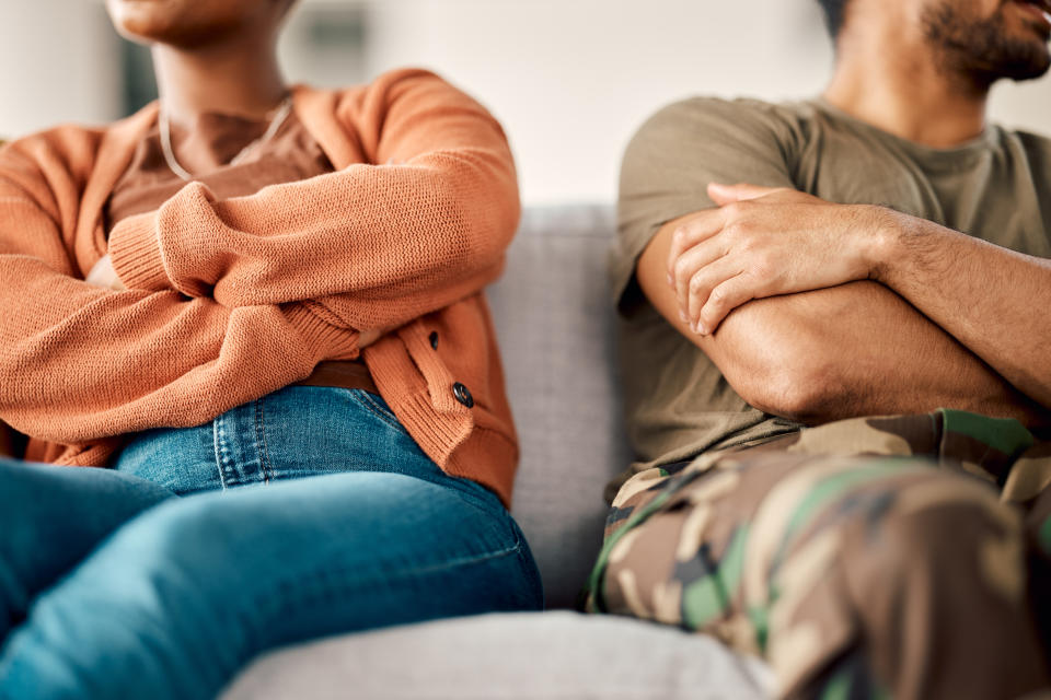 a couple sitting on the couch crossing arms