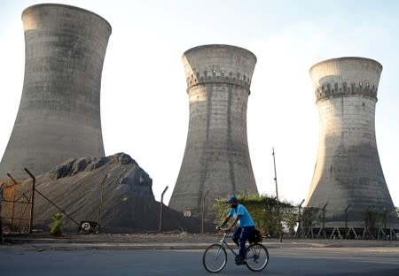 A cyclist rides past cooling towers at a local plant in Bulawayo