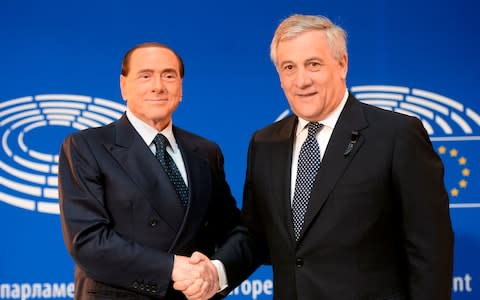 Italy's former Prime Minister Silvio Berlusconi (L) shakes hands with European Parliament President Antonio Tajani - Credit: AFP
