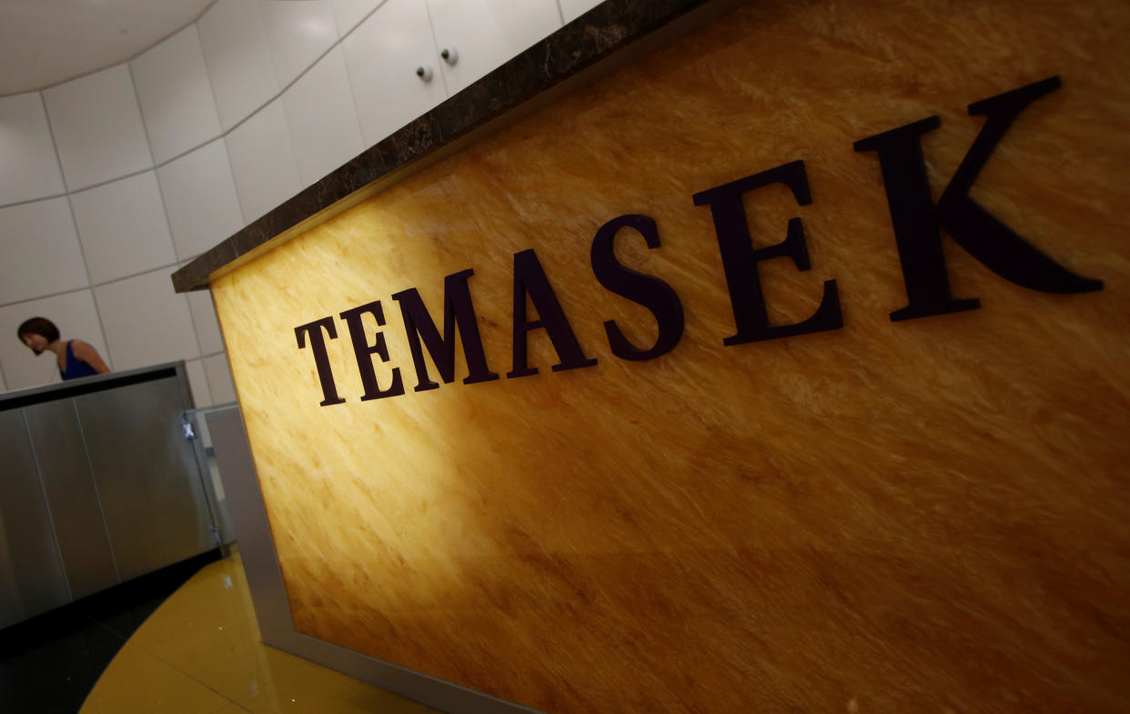 A woman passes a logo of state investor Temasek Holdings at their office in Singapore July 8, 2014. REUTERS/Edgar Su/File Photo