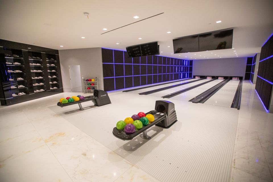 an angled side view of a four-lane bowling alley with purple, green, yellow, and red bowling balls at mansion The One Bel Air