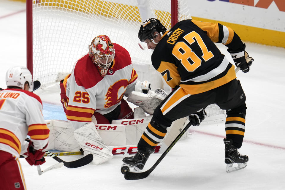 Pittsburgh Penguins' Sidney Crosby (87) gets off a pass in front of Calgary Flames goaltender Jacob Markstrom (25) during the first period of an NHL hockey game in Pittsburgh, Saturday, Oct. 14, 2023. (AP Photo/Gene J. Puskar)
