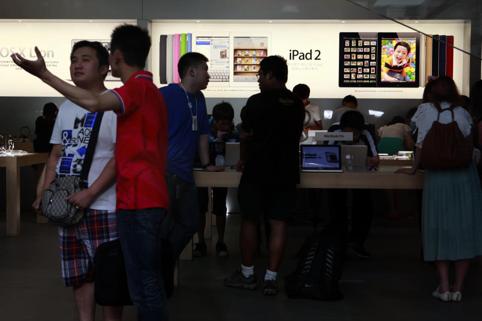 Visitors look at computer products near advertisement for Apple's iPad tablet computer at an Apple store in Beijing, China, Monday, July 2, 2012. Apple agreed to pay $60 million to settle a dispute in China over ownership of the iPad name, a court announced Monday, removing a potential obstacle to sales of the popular tablet computer in the key Chinese market. (AP Photo/Ng Han Guan)