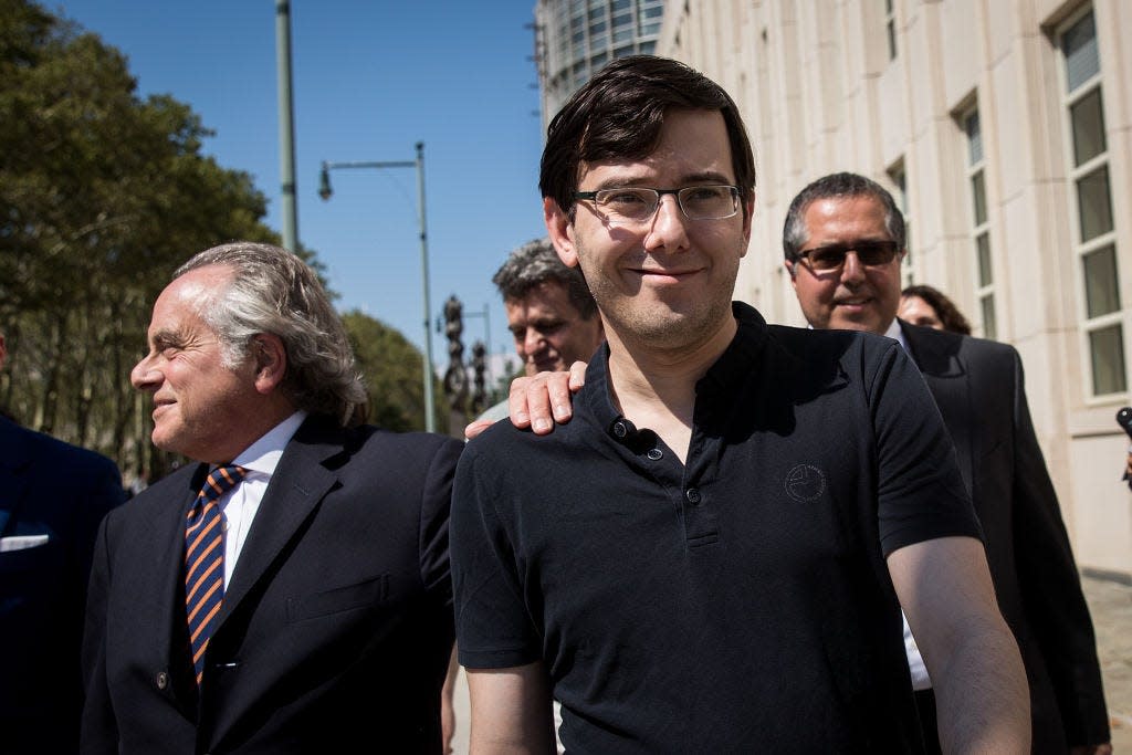 Former pharmaceutical executive Martin Shkreli, right, is seen smiling in a black short sleeved shirt with attorney Benjamin Brafman's hand on his shoulder after leaving court in New York on a sunny day August 4, 2017.