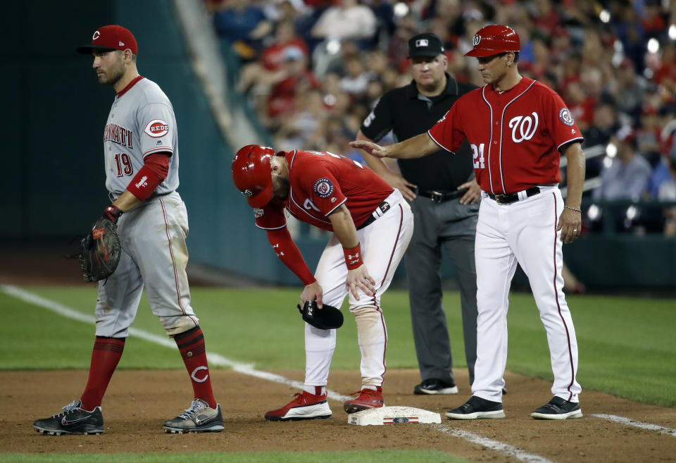Washington Nationals' Bryce Harper pauses on first base after being hit by a pitch, between Cincinnati Reds first baseman Joey Votto left, and Nationals first base coach Tim Bogar, during the sixth inning of the second baseball game of a doubleheader at Nationals Park, Saturday, Aug. 4, 2018, in Washington. (AP Photo/Alex Brandon)