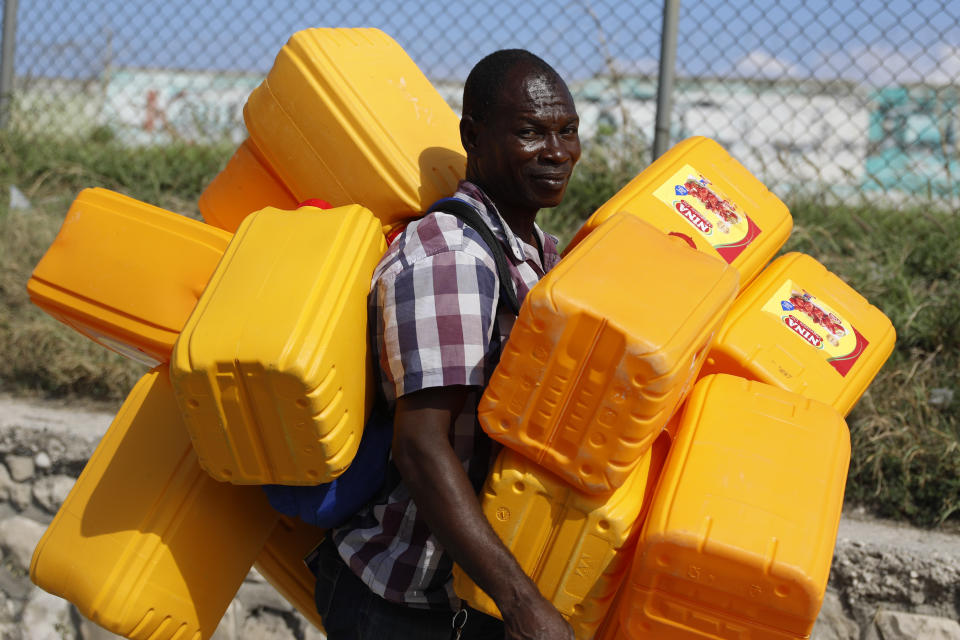 ARCHIVO - Un vendedor carga contenedores vacíos para combustible, en Puerto Príncipe, Haití, el 8 de marzo de 2024. (AP Foto/Odelyn Joseph, archivo)