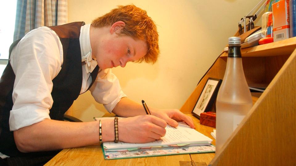 Prince Harry writing at a desk