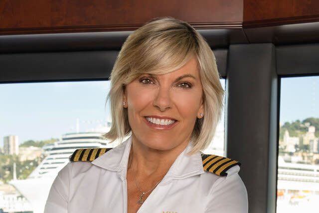 Captain Sandy smiling with her arms crossed in the wheelhouse of the yacht.