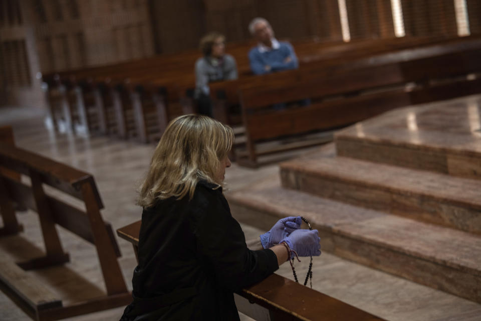 A Catholic worshipper using protective gloves prays with a rosary beads at the Santa Maria de Cana parish in Pozuelo de Alarcon, outskirts Madrid, Spain, Sunday, March 15, 2020. Pope Francis has praised people for their continuing efforts to help vulnerable communities, including the poor and the homeless, amid the coronavirus pandemic. The vast majority of people recover from the COVID-19. According to the World Health Organization, most people recover in about two to six weeks, depending on the severity of the illness. (AP Photo/Bernat Armangue)