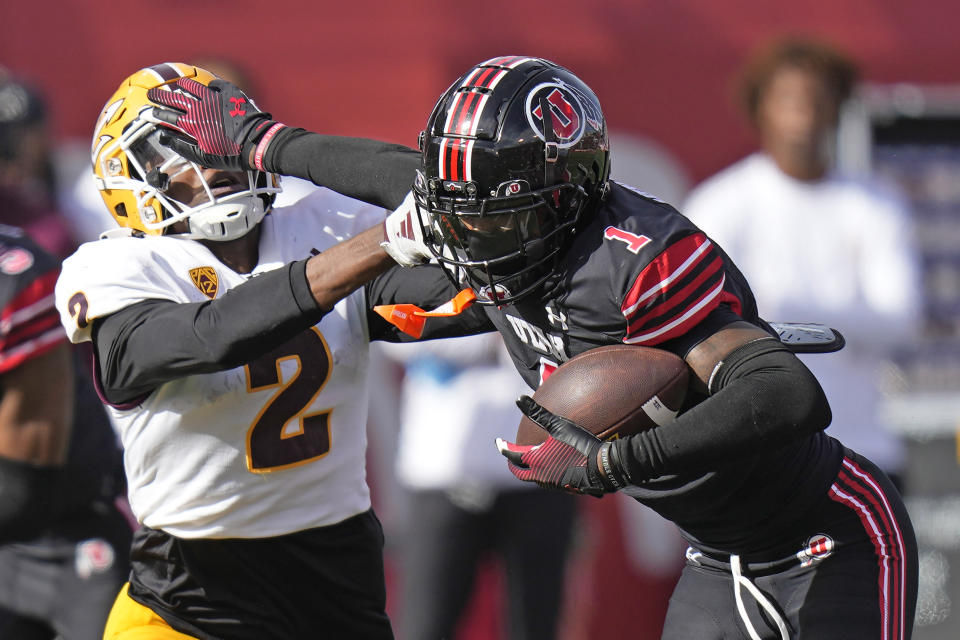 Utah cornerback Miles Battle (1) stiff arms Arizona State wide receiver Elijhah Badger (2) after his interception during the second half of an NCAA college football game Saturday, Nov. 4, 2023, in Salt Lake City. (AP Photo/Rick Bowmer)