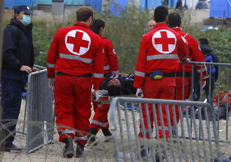 Greek medics carry a migrant who collapsed, on the border between Greece and Gevgelija, Macedonia November 22, 2015. REUTERS/Ognen Teofilovski