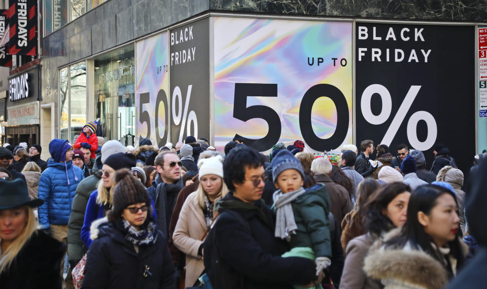 FILE - Crowds walk past a large store sign displaying a Black Friday discount in midtown New York, Friday, Nov. 23, 2018. Given higher prices and economic uncertainty, consumers face a lot of pressure this year when it comes to Black Friday and holiday season shopping. (AP Photo/Bebeto Matthews, File)