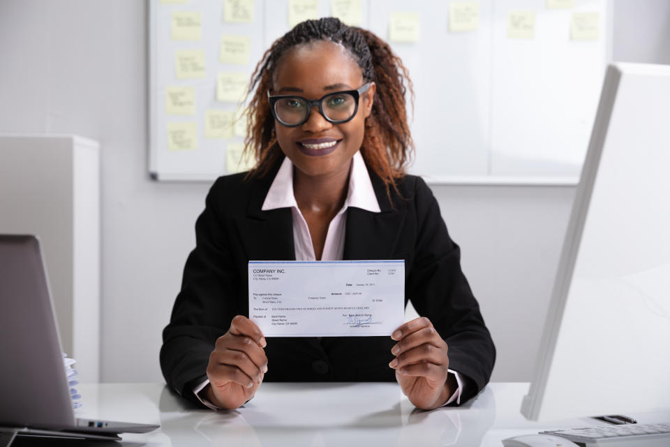 Close-up Of A Smiling Businesswoman Showing Company Cheque