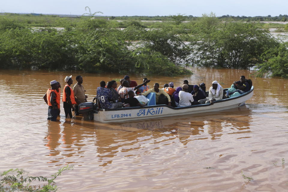 People cross a flooded area where another boat carrying a group of people has capsized at Mororo, border of Tana River and Garissa counties, North Eastern Kenya, Sunday, April 28, 2024. According to the Kenya Red Cross, 23 people have been rescued, while others still remain missing as search and rescue operations continue. Heavy rains pounding different parts of Kenya have led to dozens of deaths and the displacement of tens of thousands of people, according to the U.N. (AP Photo/Andrew Kasuku)