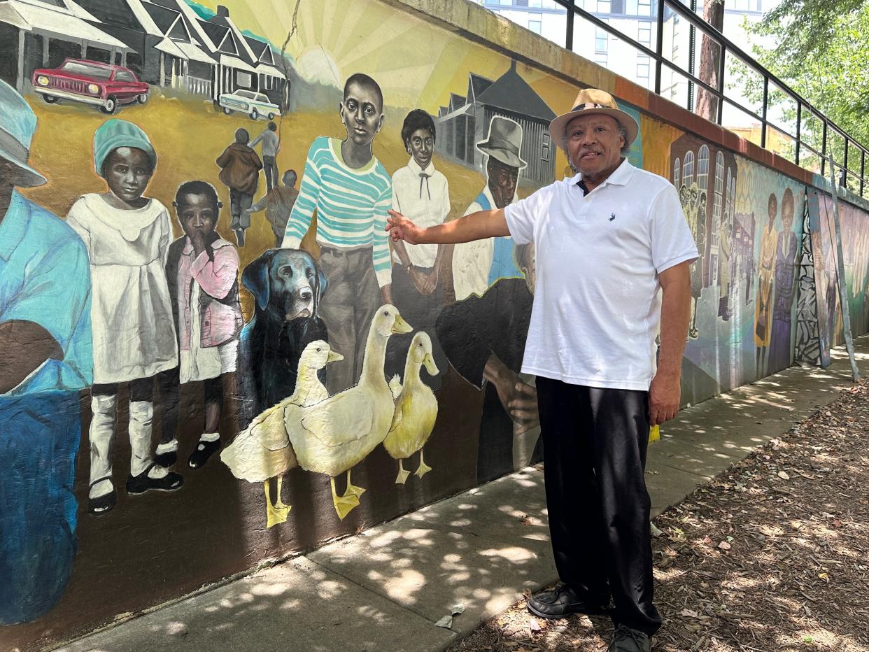 Roy Harris stands beside the Triangle Art Mural in "The Block," downtown Asheville's historically Black business district.