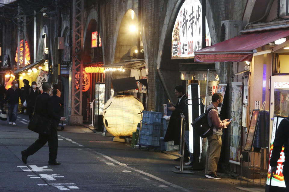 People wearing face masks to protect against the spread of the coronavirus walk on a street lined with bars and restaurants in Tokyo Wednesday, March 16, 2022. Japan’s Prime Minister Fumio Kishida on Wednesday announced plans to fully lift coronavirus restrictions on March 21 as new infections driven by the highly contagious omicron variant slow. (AP Photo/Koji Sasahara)