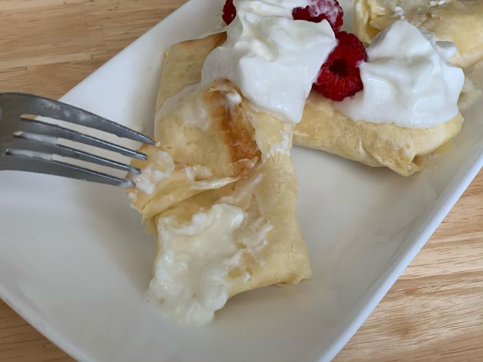 fork cutting open trader joe&#39;s blintzes on white plate