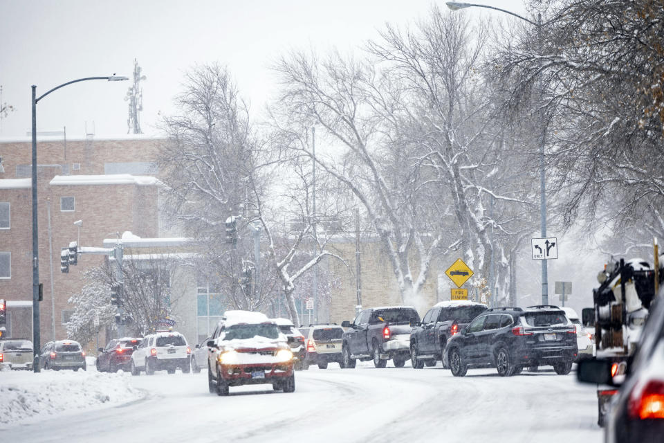 Vehicles navigate a snow-covered road, Wednesday, Oct. 25, 2023, in Helena, Mont. The first major snowstorm of the season dropped up to a foot of snow in the Helena area by Wednesday morning, canceling some school bus routes. (Thom Bridge/Independent Record via AP)