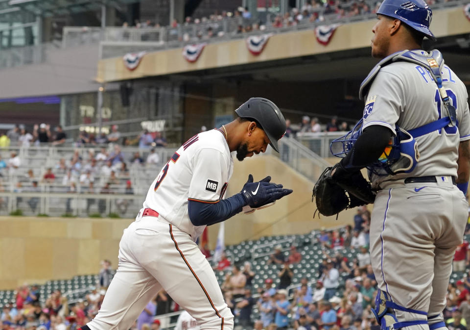 Minnesota Twins' Byron Buxton, left, applauds in front of Kansas City Royals catcher Salvador Perez, right, as he scores on his solo home run off Royals pitcher Brady Singer (51) in the first inning of a baseball game, Saturday, Sept. 11, 2021, in Minneapolis. (AP Photo/Jim Mone)