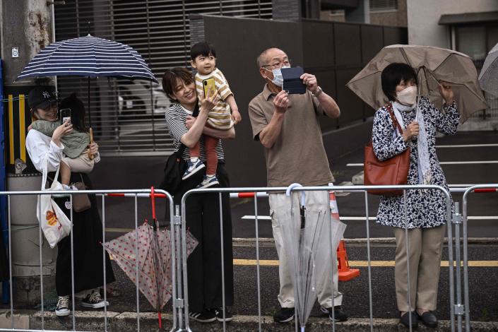 People stand along a road to see the motorcade transporting US President Joe Biden in Hiroshima on May 18, 2023, ahead of the G7 Leaders&#39; Summit.