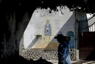 A man walks past an image of the Virgin of Guadalupe mural with text that reads in Spanish "No to the Thermo electric" in Huexca, Morelos state, Mexico, Saturday, Feb. 22, 2020. The the mural refers to a power plant that is part of a mega-energy project that includes a natural gas pipeline that traverses three states. It's at the heart of a years-long, contentious battle that calls into question the commitments of the new leftist government to indigenous land rights. (AP Photo/Eduardo Verdugo)