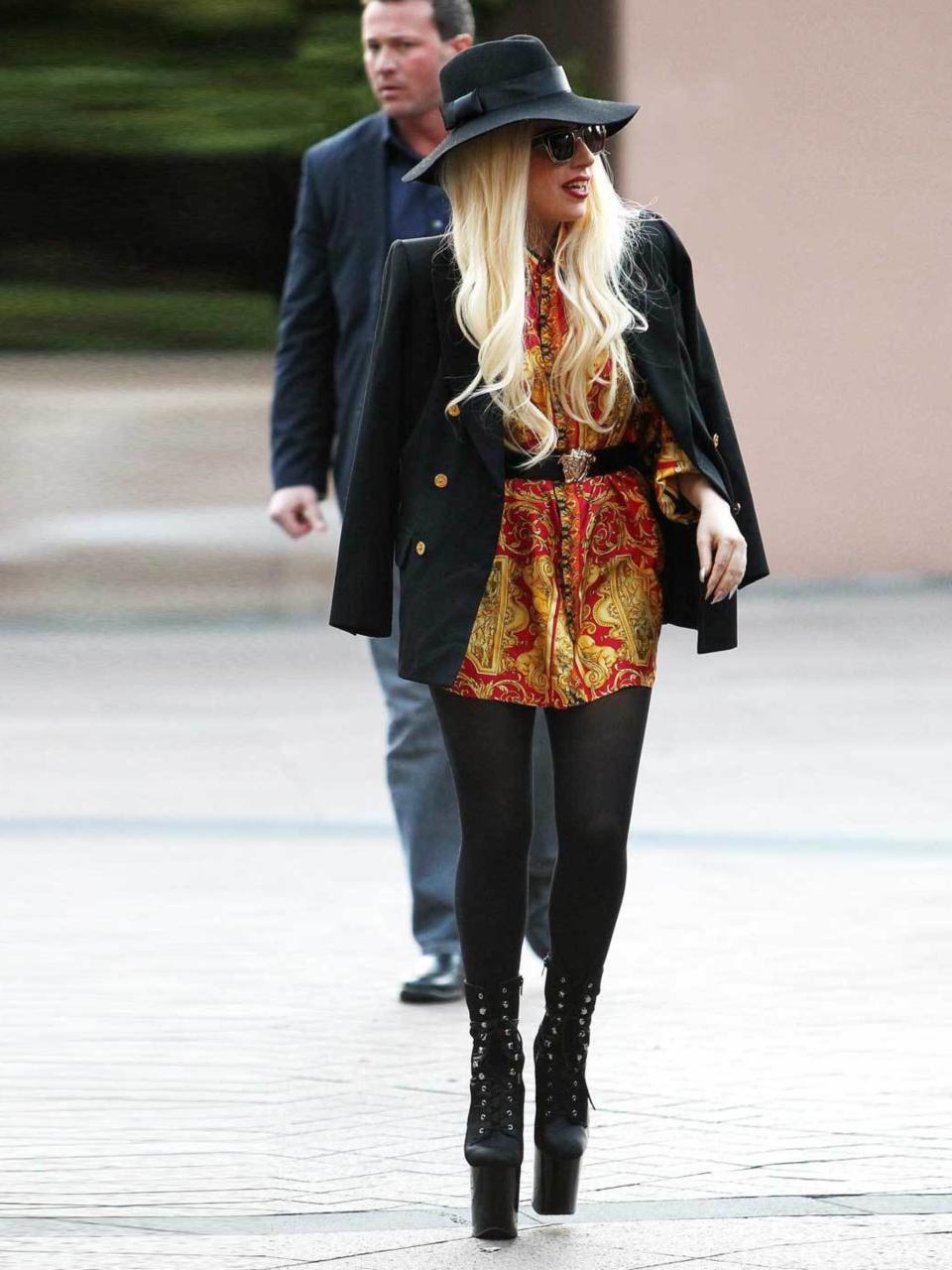 <p>Lady Gaga arrives to screaming fans in Melbourne wearing a printed dress, black jacket, hat and extra high platforms, June 2012.</p>