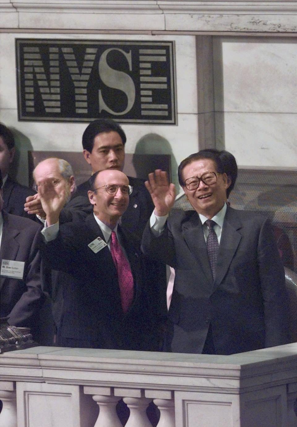 FILE - Then China's President Jiang Zemin, right, waves along with New York Stock Exchange Chairman and CEO Richard Grasso, left, moments before the Exchange's opening bell on Oct. 31, 1997, in New York. Jiang has died Wednesday, Nov. 30, 2022, at age 96.(AP Photo/Adam Nadel, File)