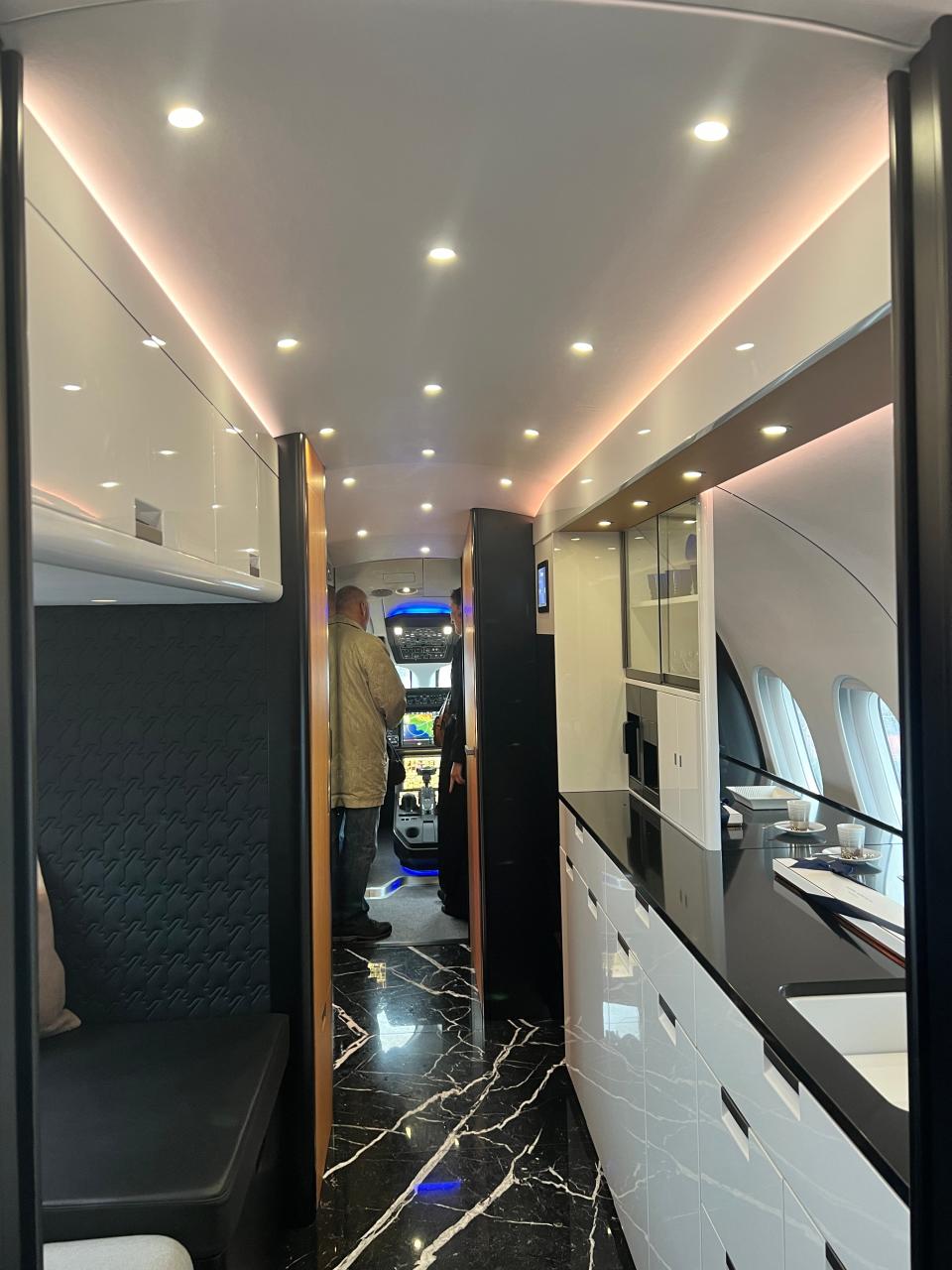 A view of the galley, white cabinets with black counter, with a striking black and white marble floor on a Falcon 10X