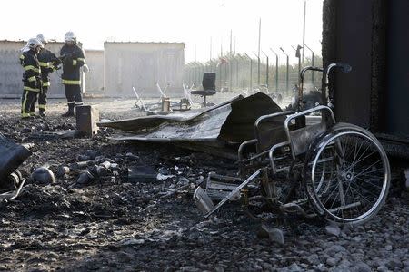 French firemen stand near debris the day after a fire destroyed large swathes of the Grande-Synthe migrant camp near Dunkirk in northern France April 11, 2017 following skirmishes on Monday that injured several people. REUTERS/Pascal Rossignol