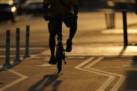 The sun sets behind a cyclist in a bike lane on Pennsylvania Avenue in Washington, Monday, May 8, 2023. (AP Photo/Carolyn Kaster)