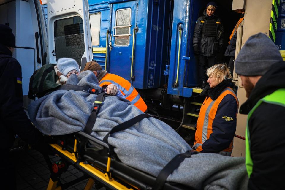 Members of the Vostok SOS team help a woman with limited mobility to get on an evacuation train in Pokrovsk, Donetsk region (AFP via Getty Images)