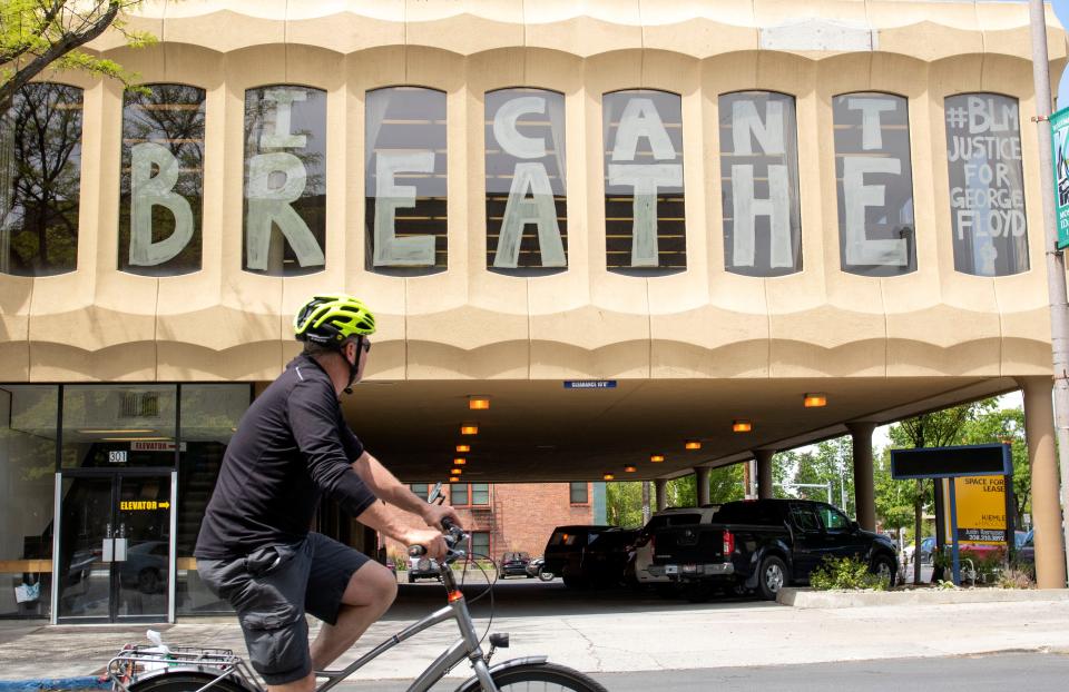 A bicyclist looks at an “I can’t breathe” sign in the window of an office building Tuesday in downtown Moscow, Idaho.