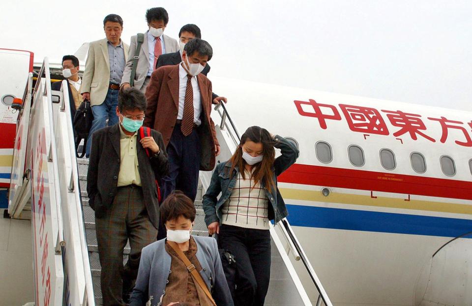 Passengers from Japan wearing protective masks get off their plane Thursday April, 17, 2003 at Pudong International Airport in Shanghai, China.