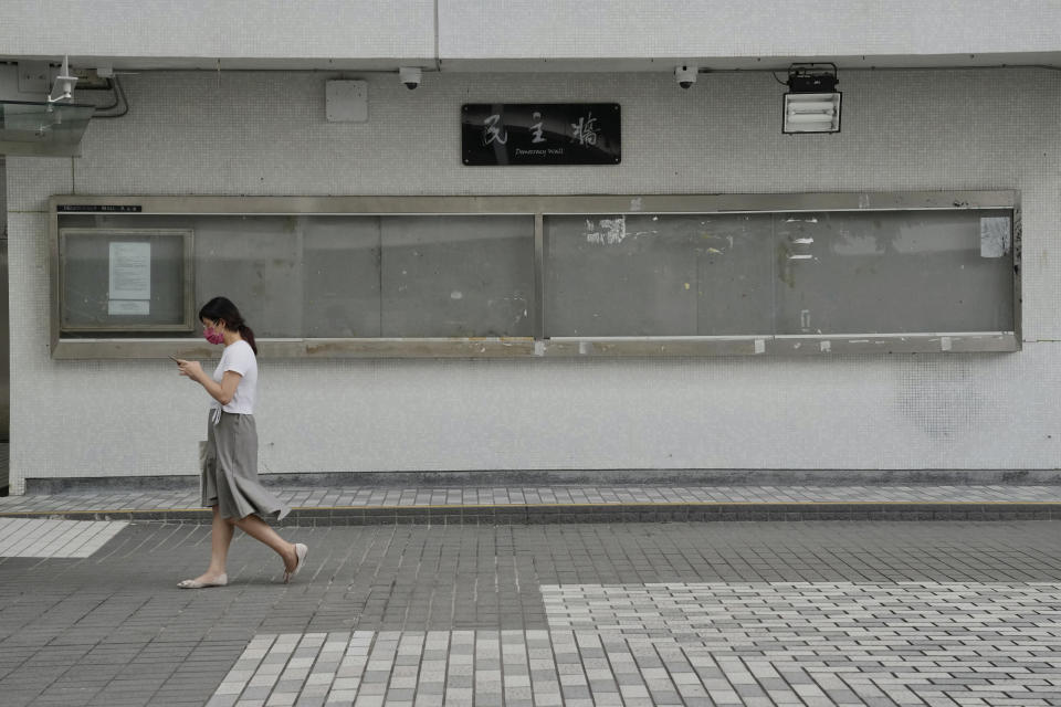 A woman walks past the notice board "Democracy Wall" which used to run by student union in campus of the University of Hong Kong, Friday, July 16, 2021. Hong Kong's national security police on Friday raided the office of a student union at the local university, after student leaders last week commemorated the death of an attacker who killed himself after stabbing a police officer. (AP Photo/Kin Cheung)