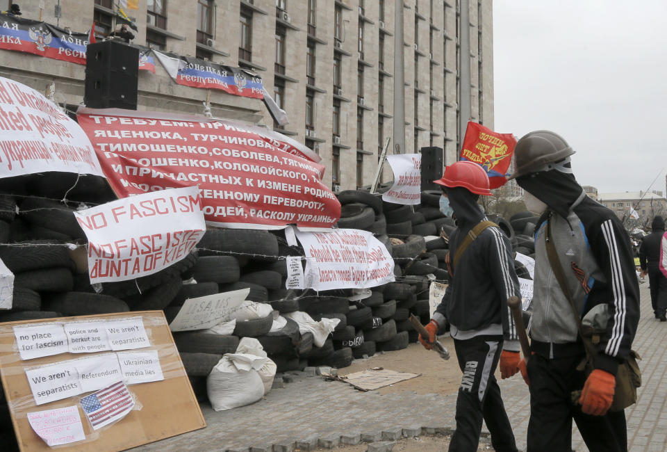 Masked pro-Russian activists pass by a barricade as they guard a regional administration building that they had seized earlier in Donetsk, Ukraine, Friday, April 11, 2014. Ukraine’s prime minister on Friday told leaders in the country’s restive east that he is committed to allowing regions to have more powers. Yatsenyuk Friday morning flew into Donetsk, where pro-Russian separatists are occupying the regional administration building and calling for a referendum that could prefigure seeking annexation by Russia. (AP Photo/Efrem Lukatsky)