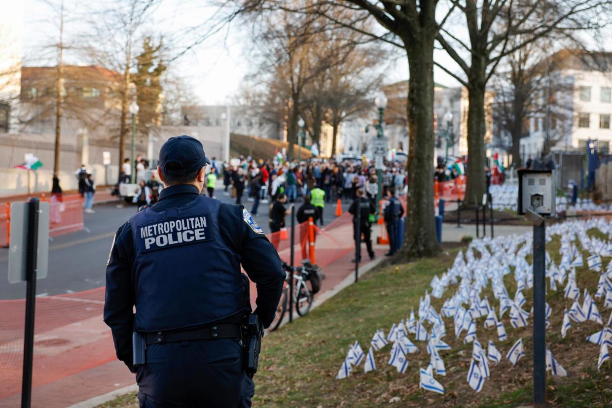 <span>A police officer stands nearby a vigil for Aaron Bushnell outside the Israeli embassy on Monday in Washington DC.</span><span>Photograph: Anna Moneymaker/Getty Images</span>