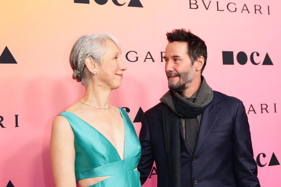 Reeves, right, and Grant exchange a sweet glance as they take photos on the red carpet.