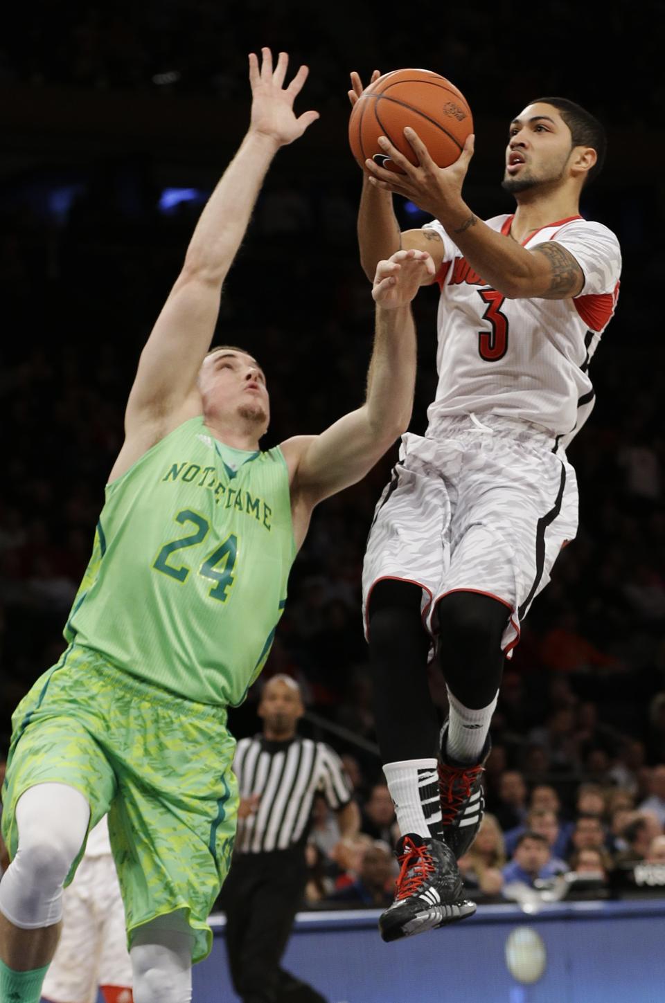 FILE - This March 15, 2013 file photo shows Louisville's Peyton Siva (3) driving past Notre Dame's Pat Connaughton (24) during the first half of an NCAA college basketball game at the Big East Conference tournament in New York. The neon-colored jerseys and camouflage-covered shorts debuted by six teams in their post-season conference championships ahead of the NCAA men's basketball tournament weren't well received in the press and social media. The changes happened to be in line with fashion runways and in recreational athleticwear, where highlighter brights and creative camo have been bona fide trends, and alternate uniforms have become part of the college football and basketball landscape, but on the court, these uniforms still made fans cringe. (AP Photo/Frank Franklin II, file)