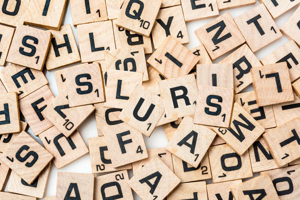 A pile of Scrabble tiles, the word SLURS in the center.
