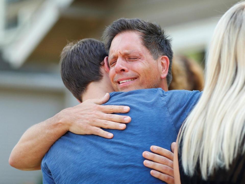 Don Damond hugs a neighbour after reading a statement about his fiance (REUTERS/Adam Bettcher)