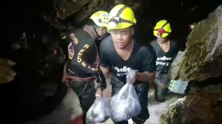 Rescuers carry supplies into the Tham Luang cave complex, where 12 boys and their soccer coach are trapped, in the northern province of Chiang Rai, Thailand, July 5, 2018. Video taken July 5, 2018. Mandatory credit RUAMKATANYU FOUNDATION/Handout via Reuters TV