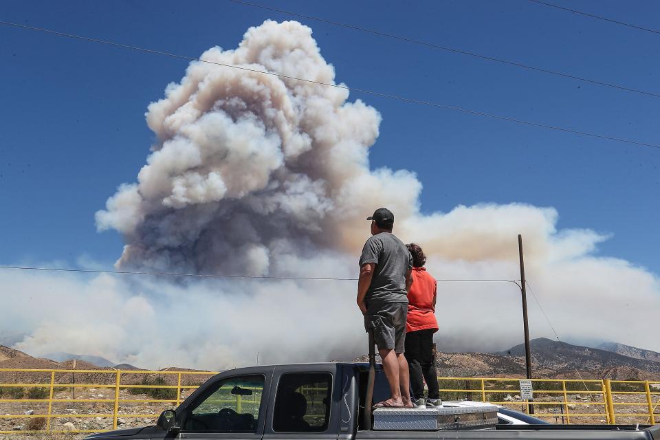 Brutencio and Marina Vidal watch as the Apple Fire burns in the foothills north of Cabazon, Calif., on August 7, 2020.  The Vidals are from nearby Banning.