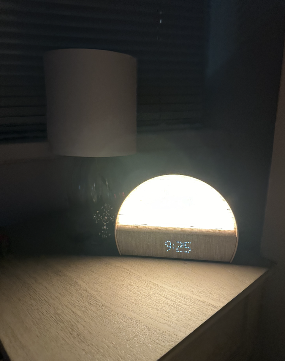 Digital clock displaying time on wooden surface with dim lighting