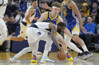 Dallas Mavericks guard Kyrie Irving, front, dribbles while being defended by Golden State Warriors guard Brandin Podziemski during the first half of an NBA basketball game in San Francisco, Tuesday, April 2, 2024. (AP Photo/Jeff Chiu)