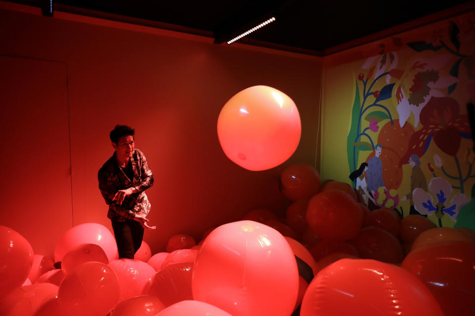 CORRECTS CITY TO LOS ANGELES - Actor Harry Shum Jr. tosses beach balls that represent mandarin oranges inside of a Lunar New Year installation Thursday, Jan. 31, 2019 in Los Angeles. Chinese fast-food chain Panda Express funded the New Year's-themed interactive exhibit inside the Westfield Century City mall. (AP Photo/Marcio Jose Sanchez)