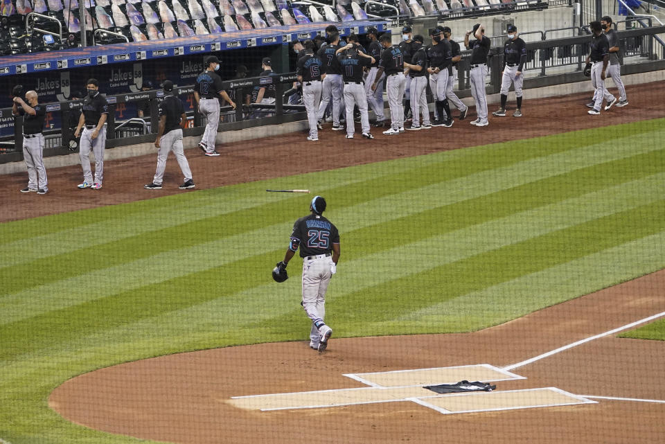 Miami Marlins center fielder Lewis Brinson walks away from home plate after placing a Black Lives Matter T-shirt on home plate as his teammates and the New York Mets walk off the field Thursday, Aug. 27, 2020, in New York. The Mets and Marlins jointly walked off the field after a moment of silence as they chose not to start their scheduled baseball game Thursday night. (AP Photo/John Minchillo)