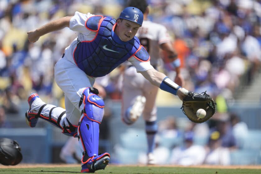 Dodgers wide receiver Will Smith (16) reaches to throw Giants center fielder Luis Matos scores Sunday at Dodger Stadium.