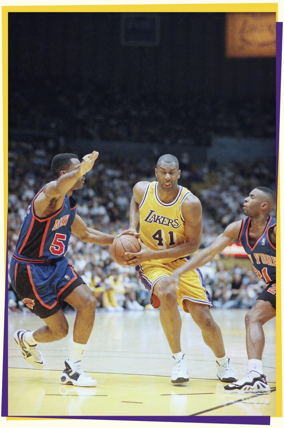Photo of a player in a Lakers jersey dribbling the ball through two opponents.