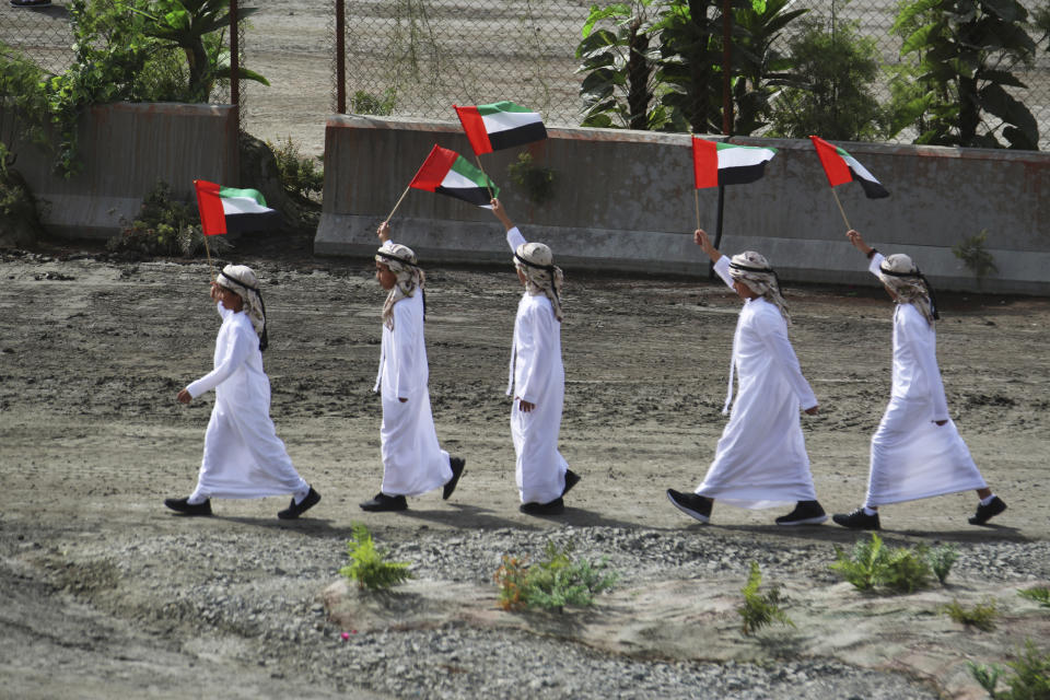 Young boys wave Emirati flags at the opening ceremony of the International Defense Exhibition and Conference in Abu Dhabi, United Arab Emirates, Sunday, Feb. 17, 2019. The biennial arms show in Abu Dhabi comes as the United Arab Emirates faces increasing criticism for its role in the yearlong war in Yemen. (AP Photo/Jon Gambrell)
