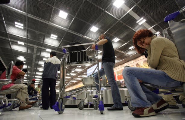 Bangkok, THAILAND:  A passenger (R), arrived from the first flight, holds her head in frustration after extra ordinary delay in baggage arrivals during the opening day of Bangkok's new Suvarnabhumi airport, 28 September 2006. Passengers at Bangkok's new international airport faced delays in collecting their bags and checking in on the first full day of operations because of computer and mechanical glitches.    AFP PHOTO / Saeed KHAN  (Photo credit should read SAEED KHAN/AFP/Getty Images)